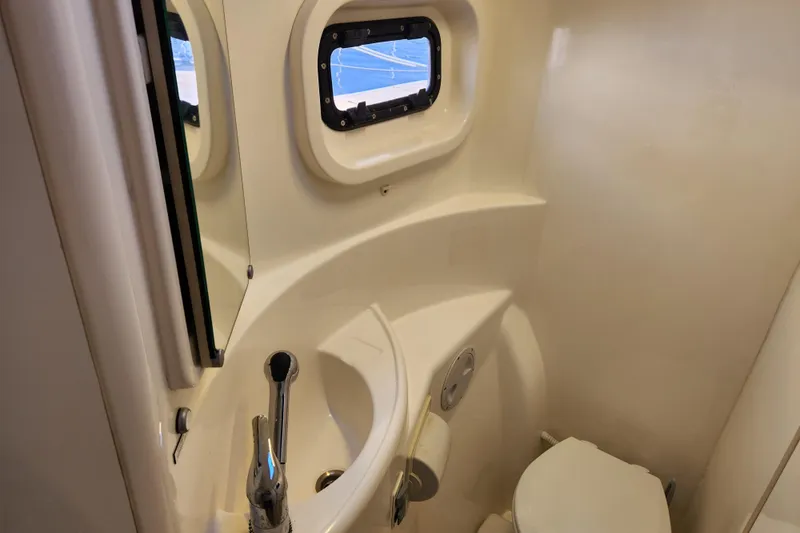 Cara Lynn Yacht Photos Pics Compact bathroom in a 2015 Leopard 44 yacht with sink, toilet, and porthole window.