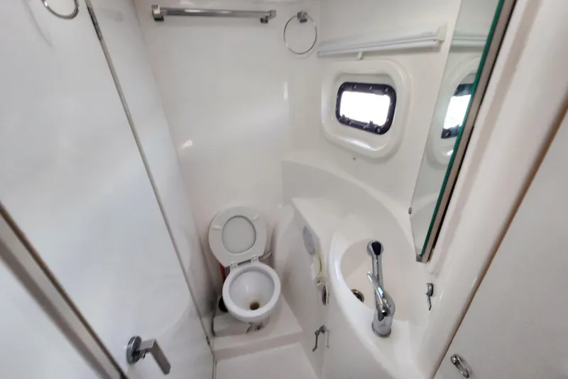 Cara Lynn Yacht Photos Pics Compact bathroom in a 2015 Leopard 44 yacht with toilet, sink, and porthole window.