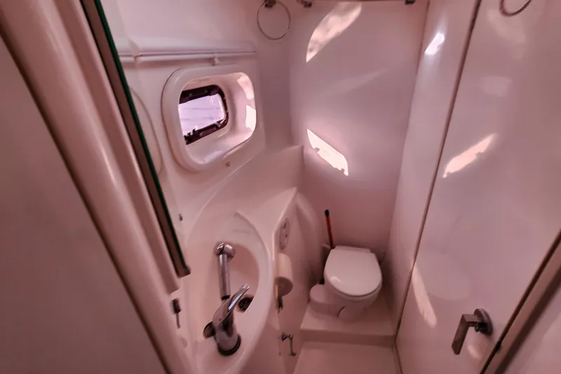 Cara Lynn Yacht Photos Pics Compact bathroom in a 2015 Leopard 44 yacht, featuring a toilet, sink, and porthole window.
