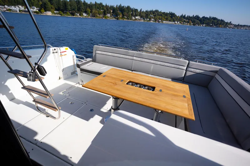 Samadhi Yacht Photos Pics 2024 Jeanneau NC 1295 Fly yacht deck with seating and wooden table on a sunny day.