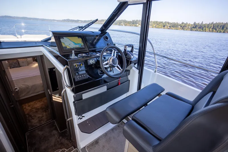 Samadhi Yacht Photos Pics 2024 Jeanneau NC 1295 Fly cockpit with navigation system, steering wheel, and comfortable seating.