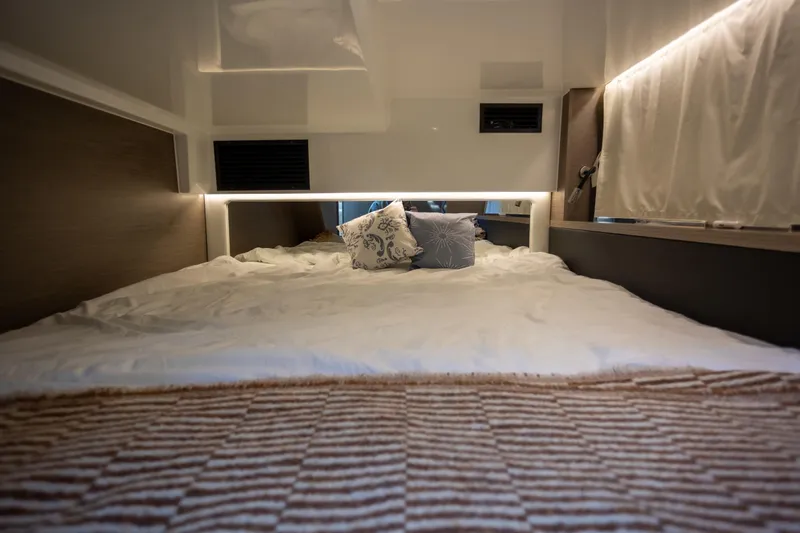 Samadhi Yacht Photos Pics Luxurious cabin interior of 2024 Jeanneau NC 1295 Fly with cozy bedding and ambient lighting.