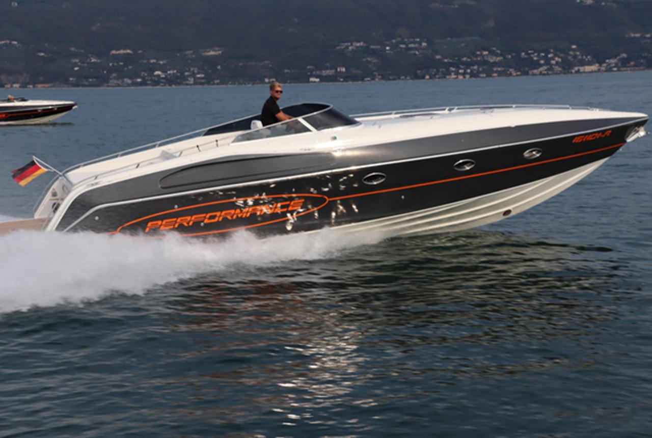 High-speed 2022 Performance 1201 powerboat cruising on a lake with scenic background.