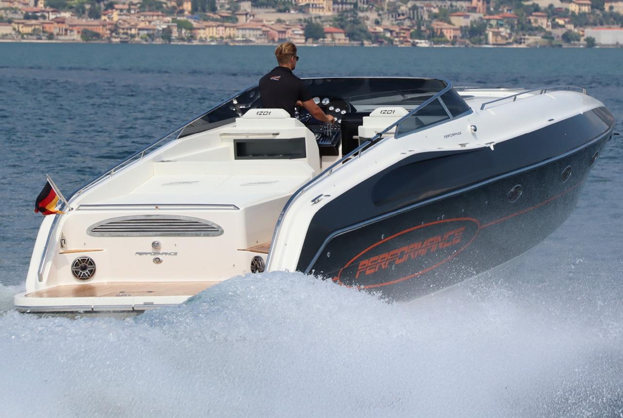 2022 Performance 1201 speedboat cruising on a lake with a scenic city backdrop.