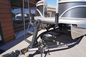 2024 Sun Tracker Party Barge 20 DLX on trailer, parked outside a building.