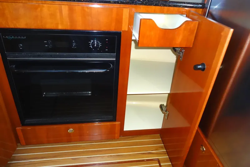 Lit Up Yacht Photos Pics 2007 Meridian 459 yacht kitchen with oven, wooden cabinets, and open storage.
