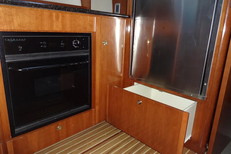 Lit Up Yacht Photos Pics 2007 Meridian 459 yacht kitchen with oven, stainless steel fridge, and wooden cabinetry.