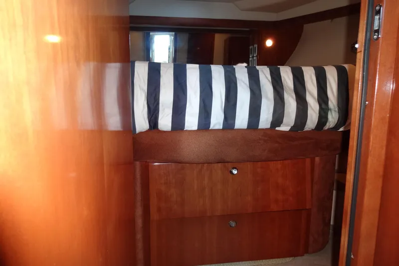 Lit Up Yacht Photos Pics Interior cabin of 2007 Meridian 459 yacht with striped bedding and wooden cabinetry.