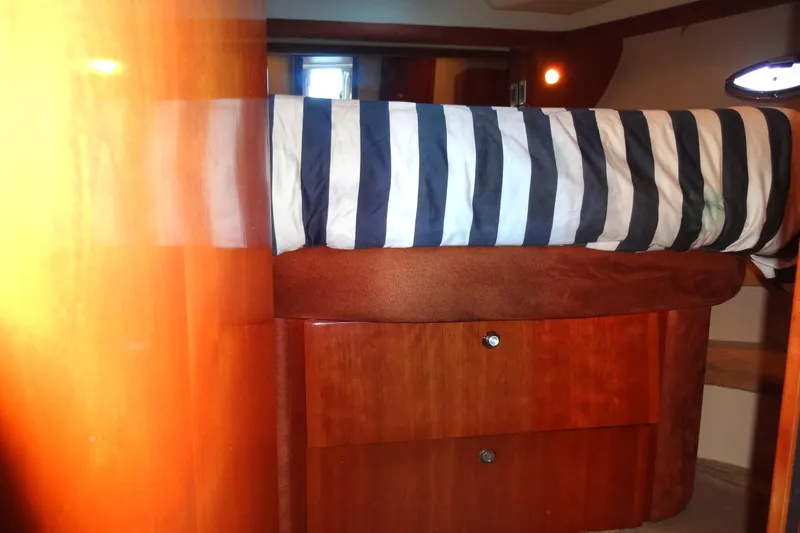 Lit Up Yacht Photos Pics Luxurious 2007 Meridian 459 yacht cabin with striped bedding and wooden storage drawers.