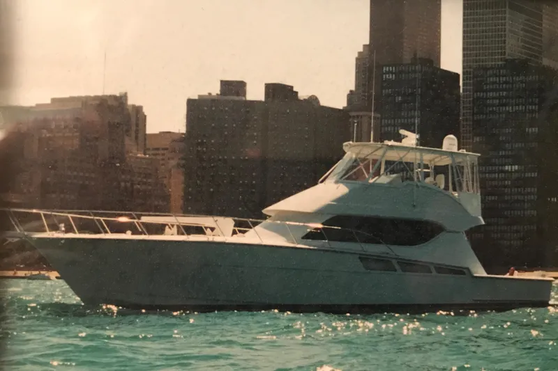 Rollwind Yacht Photos Pics 2001 Hatteras 55 Convertible yacht cruising near city skyline.