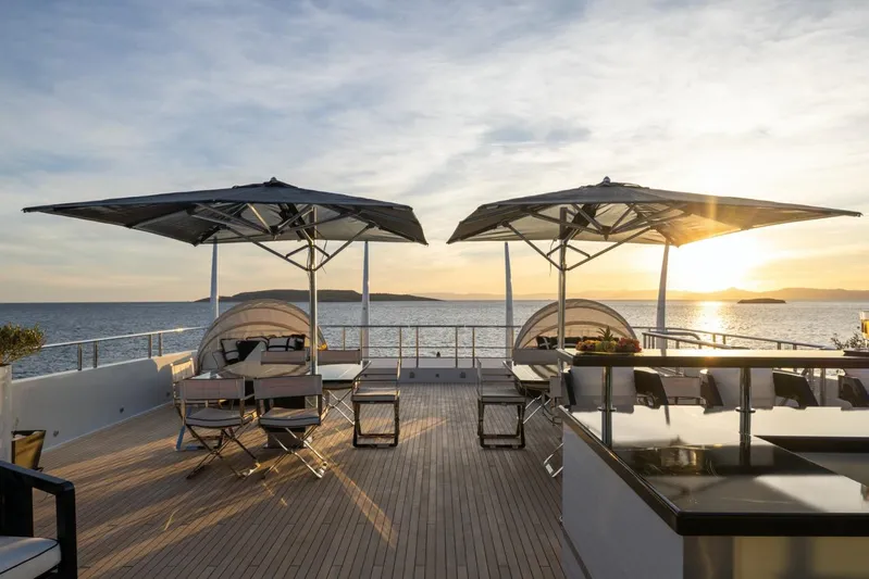 Alfa G Yacht Photos Pics Luxurious Oceanco 60-meter yacht deck with seating, umbrellas, and ocean sunset view, built in 2004.