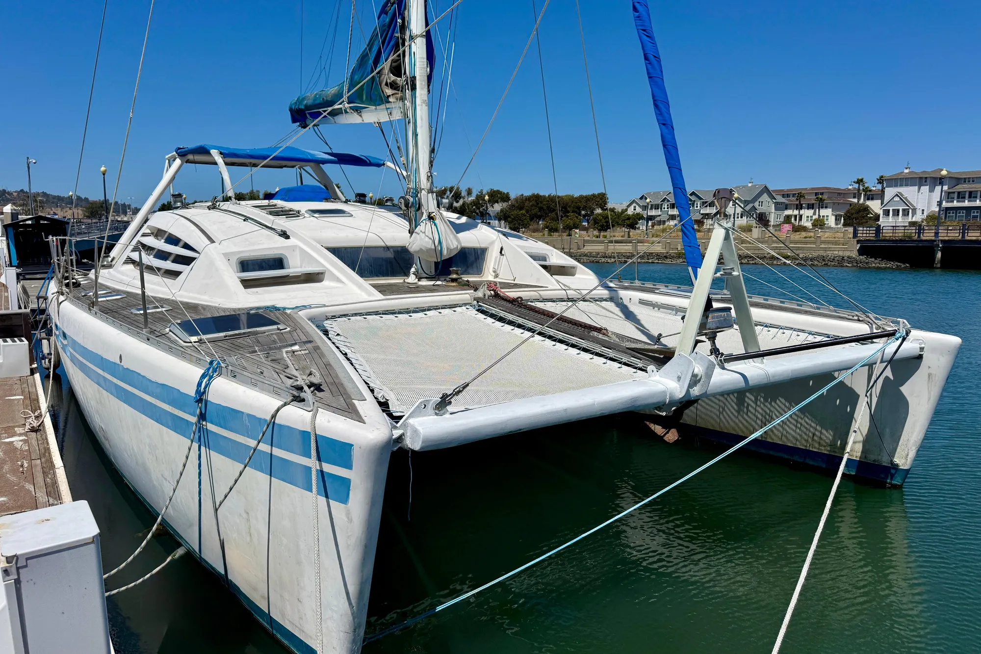 1992 Wauquiez Kronos catamaran docked in a marina under clear blue skies.