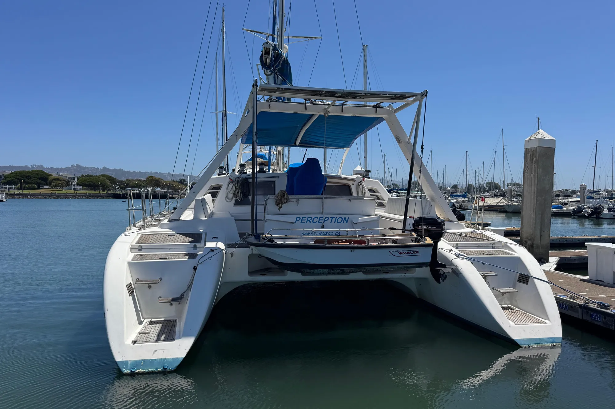 1992 Wauquiez Kronos catamaran docked in a marina under clear blue skies.