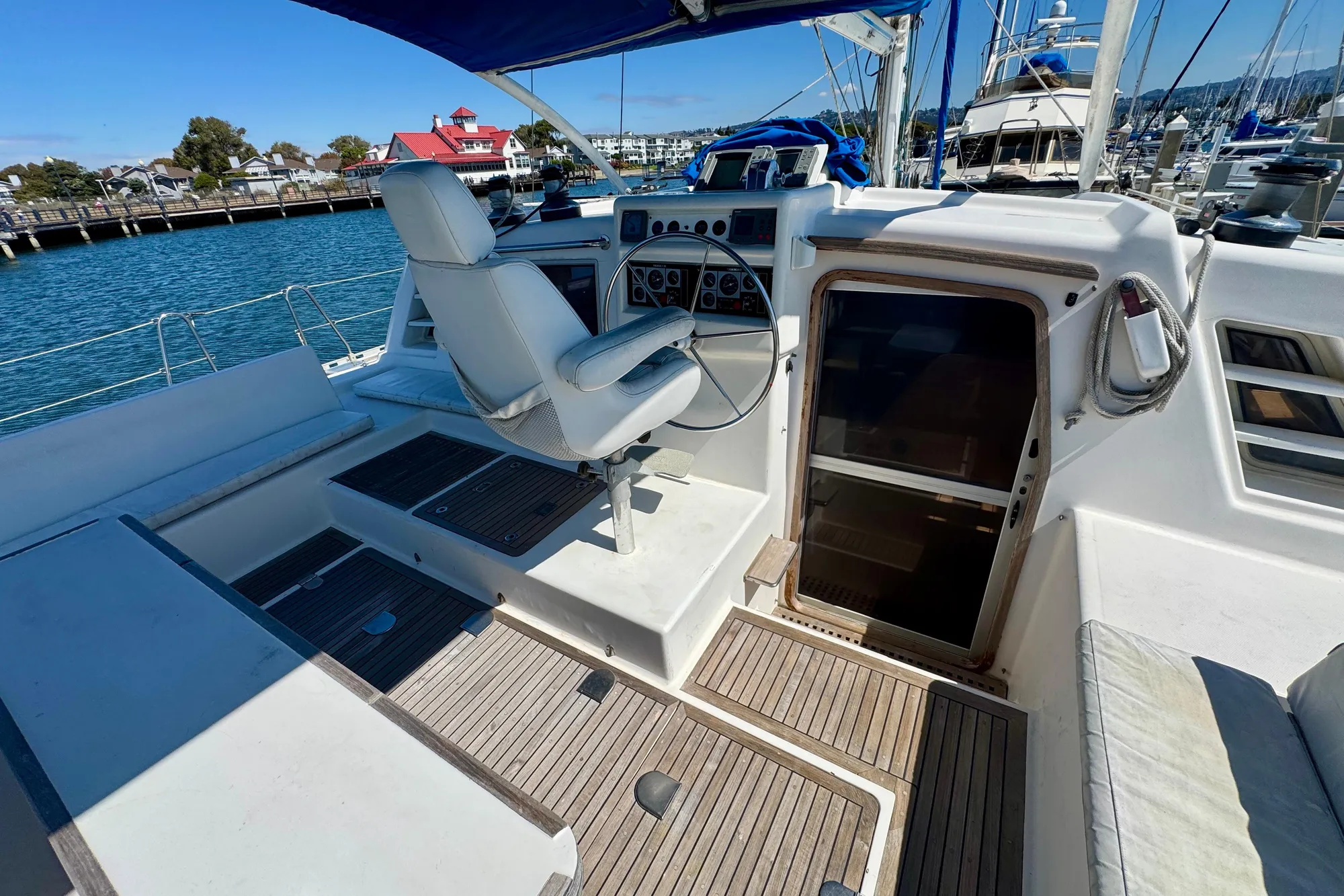 Cockpit of 1992 Wauquiez Kronos sailboat with steering wheel and seating, docked at marina.