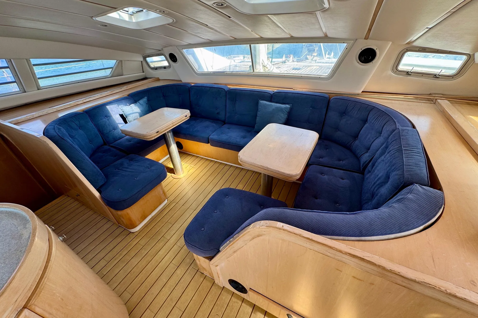 Luxurious 1992 Wauquiez Kronos yacht interior with blue cushioned seating and wooden flooring.