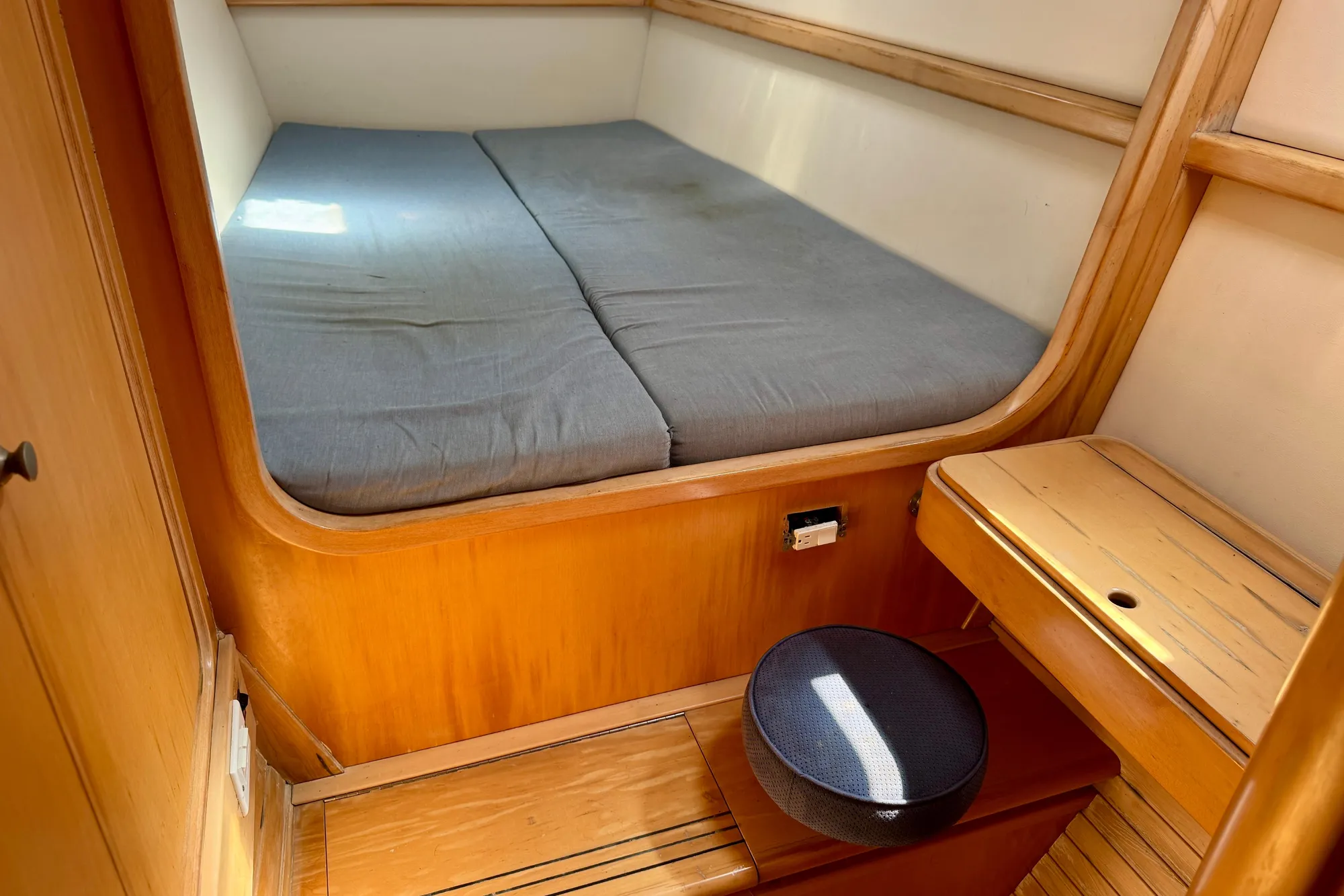 Cozy cabin interior of 1992 Wauquiez Kronos sailboat with wooden furnishings and a cushioned bed.