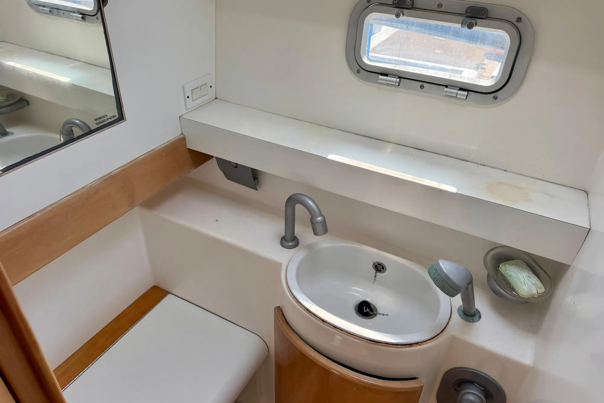 Bathroom interior of 1992 Wauquiez Kronos yacht with sink, mirror, and porthole window.