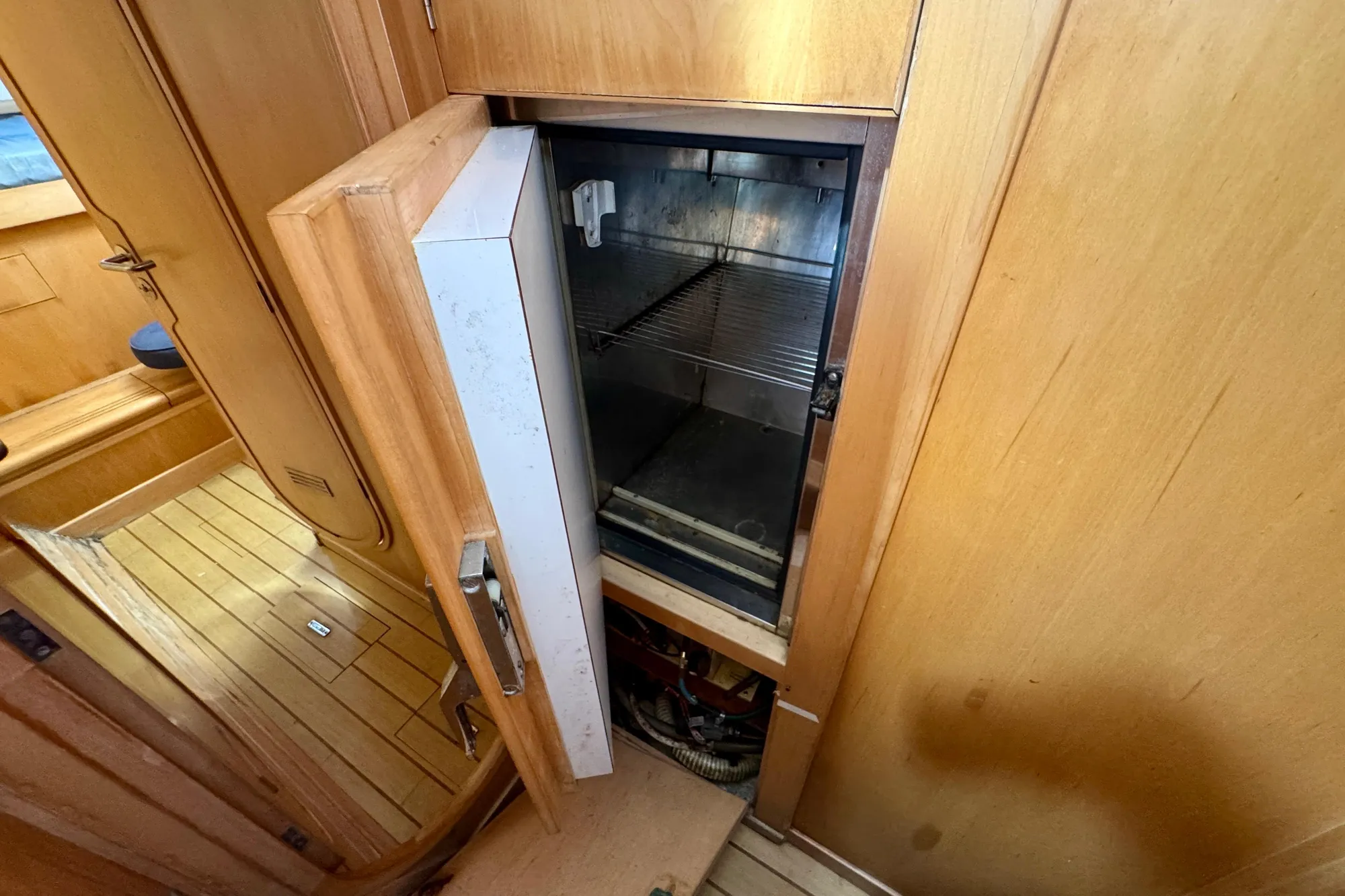 1992 Wauquiez Kronos yacht interior with open wooden cabinet and built-in refrigerator.