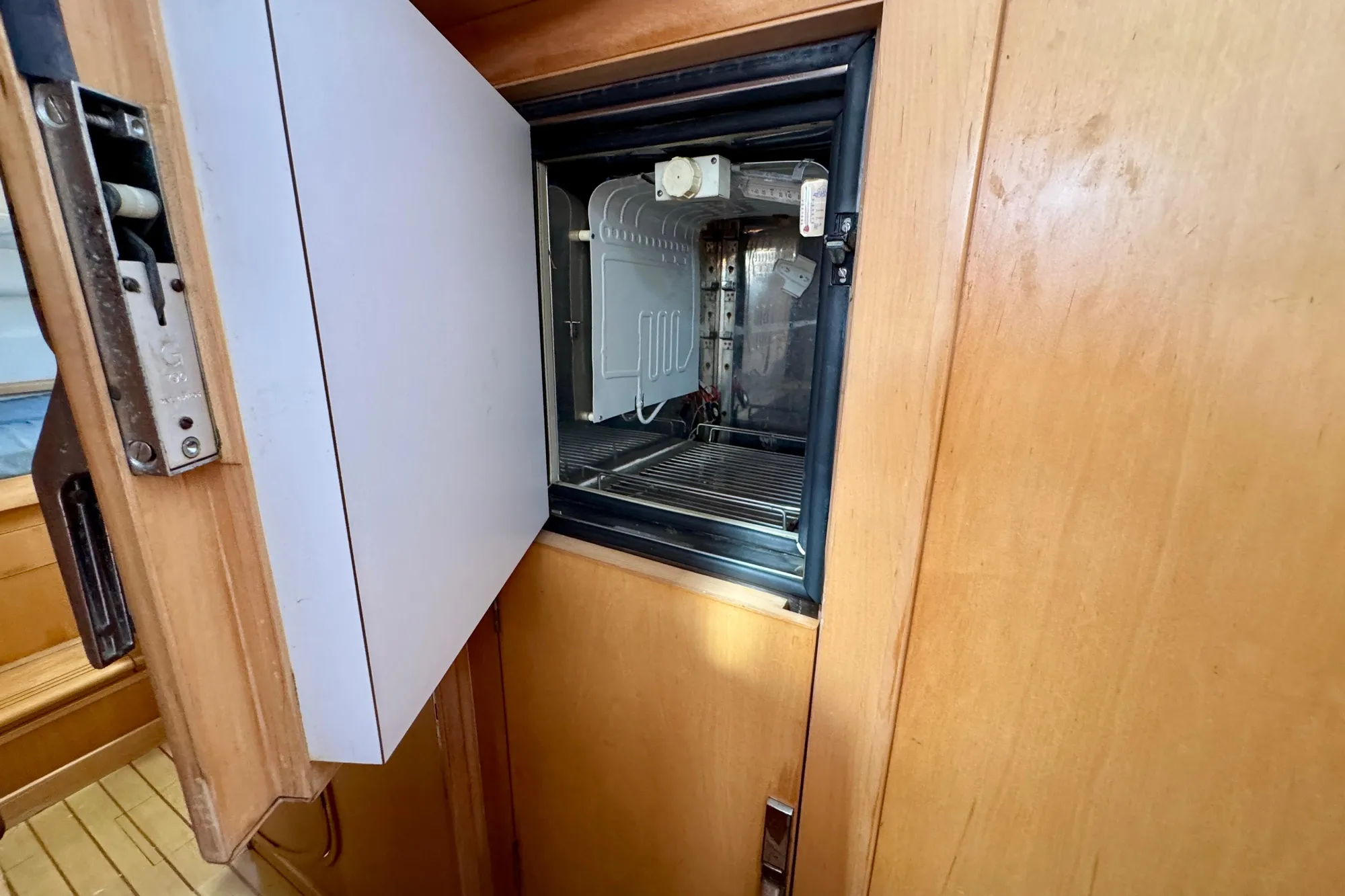 Open refrigerator inside 1992 Wauquiez Kronos yacht, wooden interior.