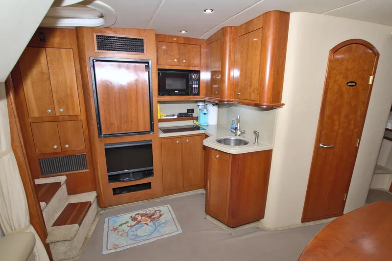High Hopes Yacht Photos Pics 2004 Cruisers Yachts 370 Express interior with kitchenette, wooden cabinets, and carpeted flooring.