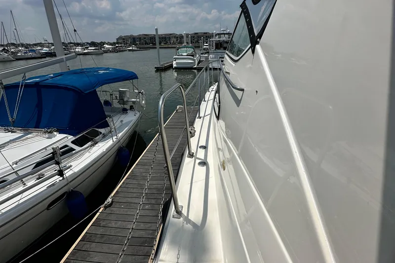 Knot Available Yacht Photos Pics 2004 Cruisers Yachts 405 Express Motoryacht docked beside sailboat in marina.