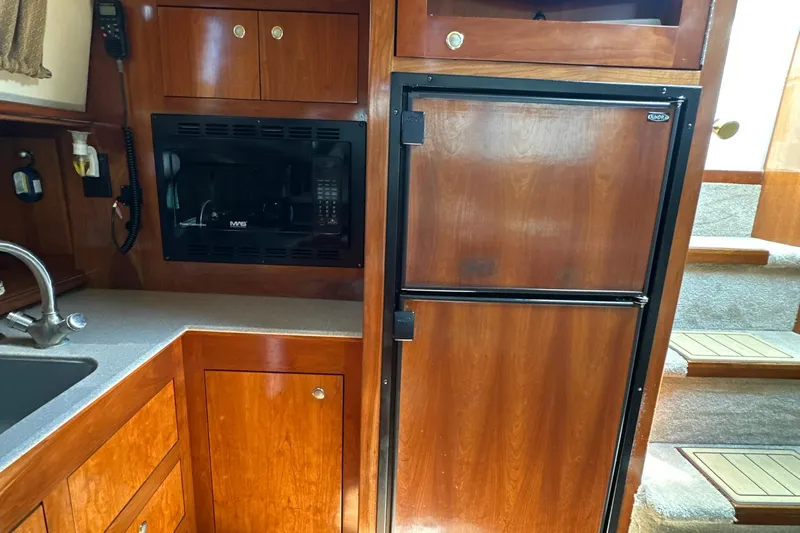 Knot Available Yacht Photos Pics 2004 Cruisers Yachts 405 Express Motoryacht kitchen with wood cabinetry and appliances.