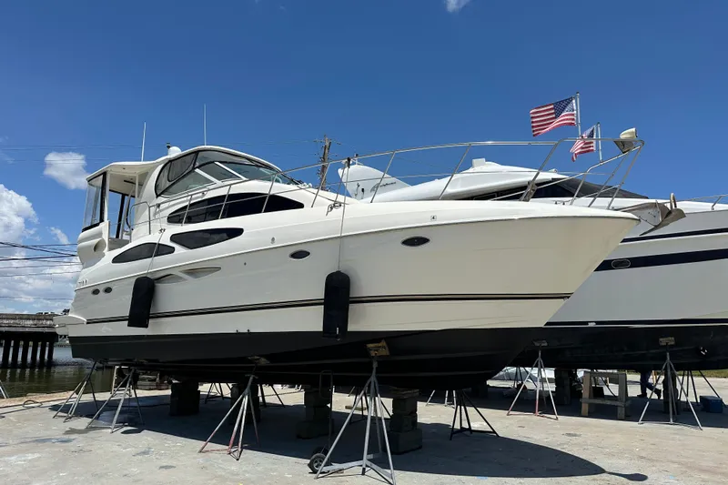 Knot Available Yacht Photos Pics 2004 Cruisers Yachts 405 Express Motoryacht on stands, with American flag, under clear blue sky.