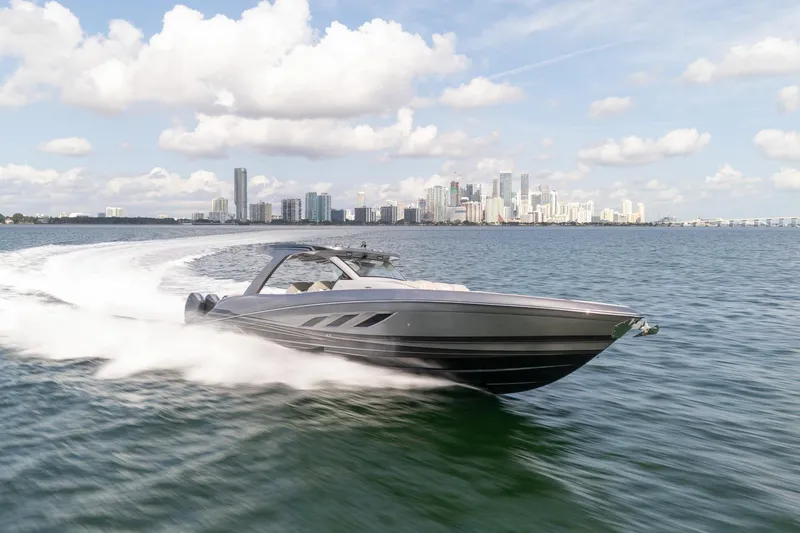  Yacht Photos Pics 2026 Deep Impact 499 Sport speedboat cruising near city skyline on a sunny day.
