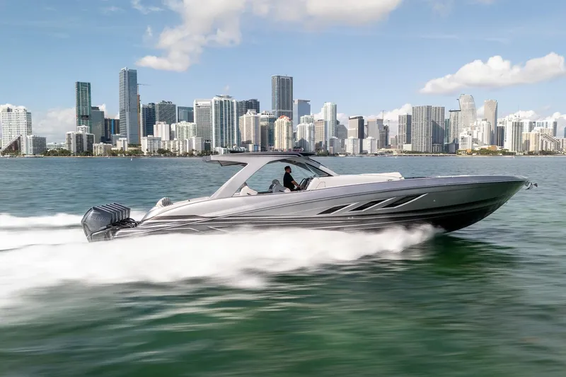  Yacht Photos Pics 2026 Deep Impact 499 Sport boat speeding on water with city skyline backdrop.