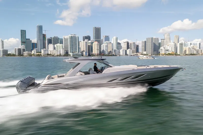  Yacht Photos Pics 2026 Deep Impact 499 Sport boat cruising near city skyline on a sunny day.