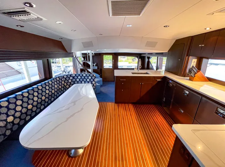 Soteria Yacht Photos Pics Luxurious interior of 1999 Hatteras 70 Convertible yacht with modern kitchen and seating area.