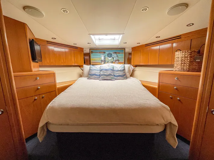 Soteria Yacht Photos Pics Luxurious cabin interior of 1999 Hatteras 70 Convertible yacht with cozy bed and wooden cabinetry.