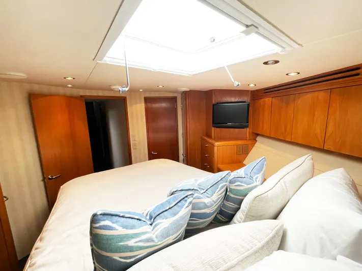 Soteria Yacht Photos Pics Luxurious bedroom interior of 1999 Hatteras 70 Convertible yacht with modern amenities.