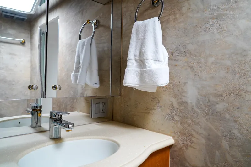 Soteria Yacht Photos Pics Luxurious bathroom interior of 1999 Hatteras 70 Convertible yacht with elegant fixtures and towel.