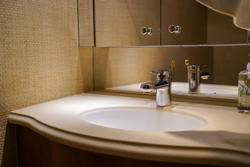 Soteria Yacht Photos Pics Luxurious bathroom sink in 1999 Hatteras 70 Convertible yacht, featuring elegant fixtures and mirrored cabinet.