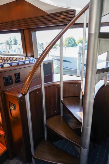 Soteria Yacht Photos Pics Spiral staircase inside 1999 Hatteras 70 Convertible yacht with wooden and metal design.