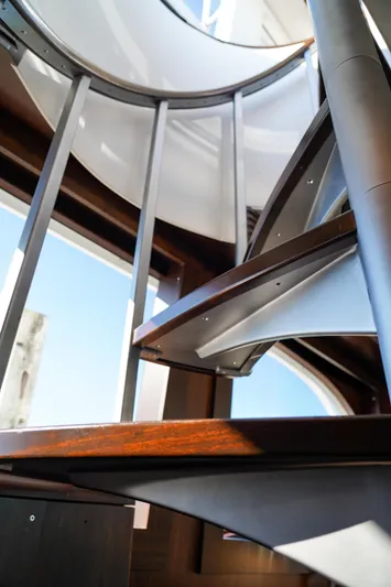 Soteria Yacht Photos Pics Spiral staircase on 1999 Hatteras 70 Convertible yacht, showcasing modern design and craftsmanship.