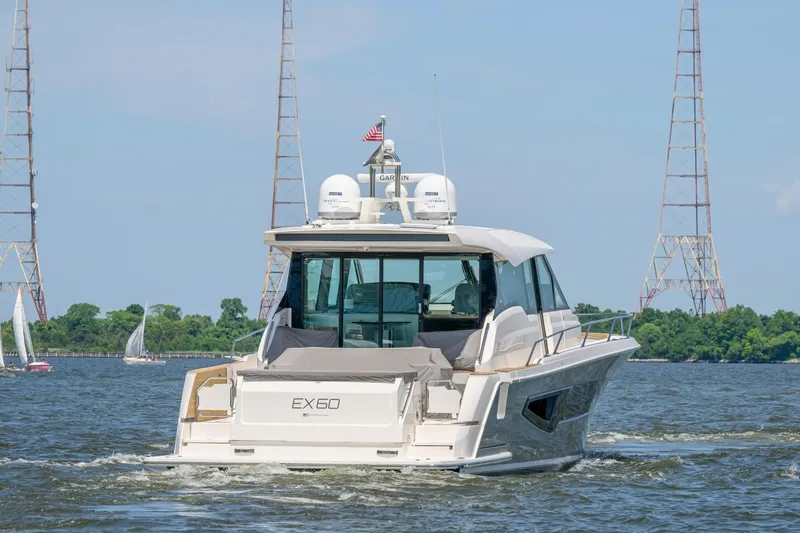 Jack's Boat Yacht Photos Pics 2024 Tiara Yachts EX 60 cruising on a scenic waterway with sailboats and towers.