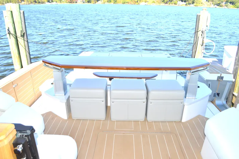 Jack's Boat Yacht Photos Pics 2024 Tiara Yachts EX 60 deck with seating and table, overlooking serene water.