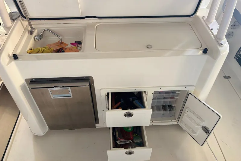 Pier Pressure Yacht Photos Pics 2018 Cobia 344 Center Console boat kitchen area with sink, storage, and refrigerator.
