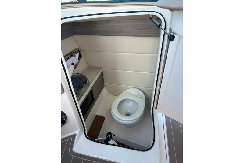  Yacht Photos Pics 2019 Regal 29 OBX boat interior bathroom with compact toilet and storage shelf.