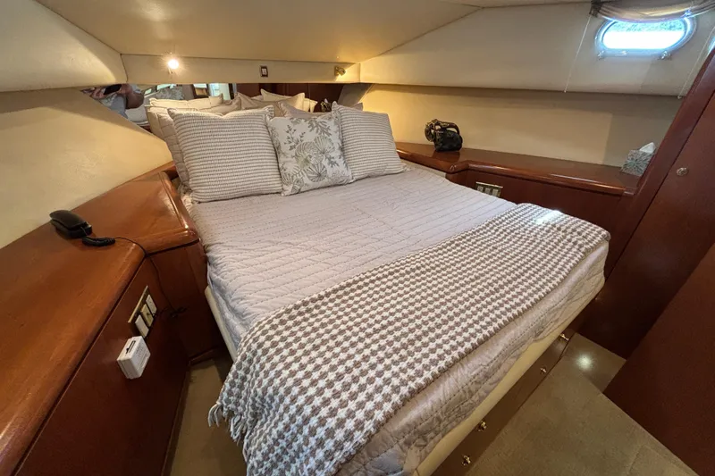 Tahoe Yacht Photos Pics Cozy bedroom interior of a 1996 Queenship yacht with elegant bedding and wooden accents.