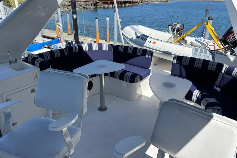 Tahoe Yacht Photos Pics Luxurious 1996 Queenship yacht deck with seating and a small boat in the background.