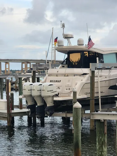 Dilligaf Yacht Photos Pics 2020 Regal 38 XO yacht docked with triple outboard engines, flags, and a bridge in the background.