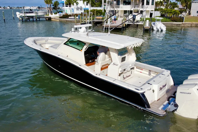  Yacht Photos Pics 2024 Scout 425 LXF boat docked in a marina, featuring sleek design and Mercury engines.