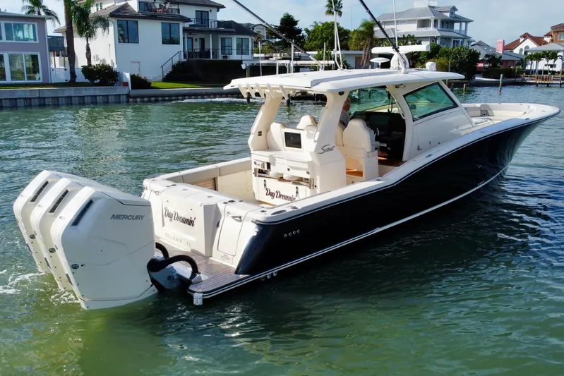  Yacht Photos Pics 2024 Scout 425 LXF boat with triple Mercury engines on a scenic waterfront.
