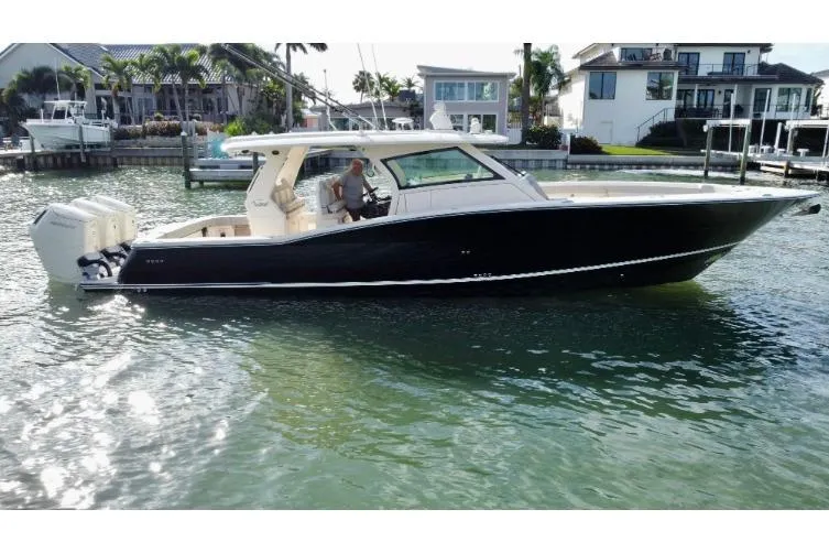  Yacht Photos Pics 2024 Scout 425 LXF boat on water near waterfront homes.