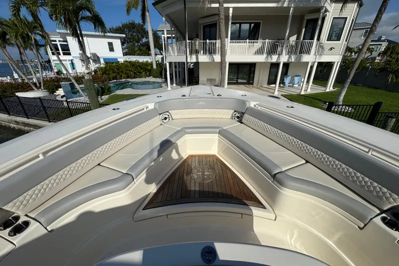  Yacht Photos Pics 2024 Scout 425 LXF boat interior with luxurious seating and wooden deck, near waterfront home.