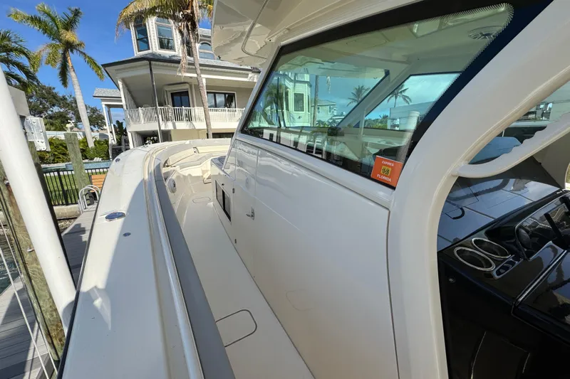  Yacht Photos Pics 2024 Scout 425 LXF boat docked near a waterfront home with palm trees.