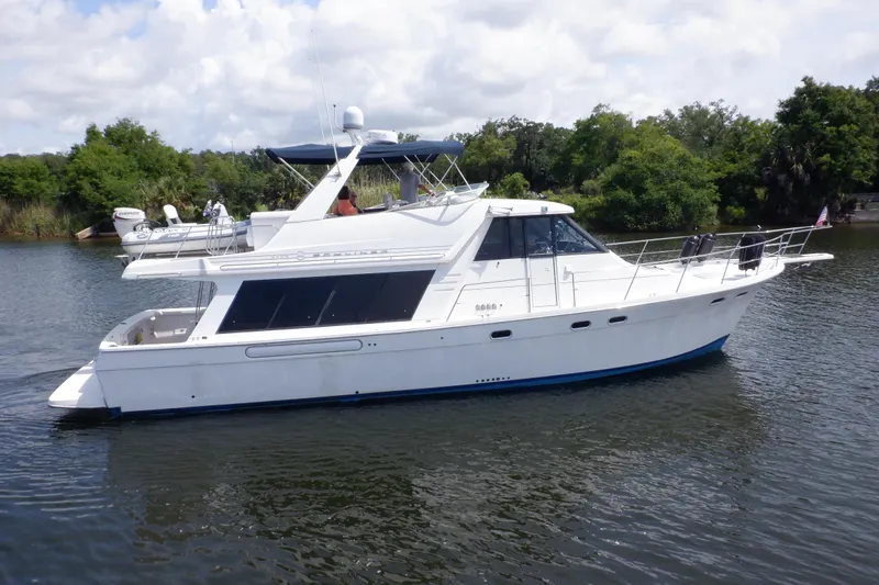 Epic Yacht Photos Pics 1998 Bayliner 4788 Pilot House Motoryacht cruising on a calm river with lush greenery.